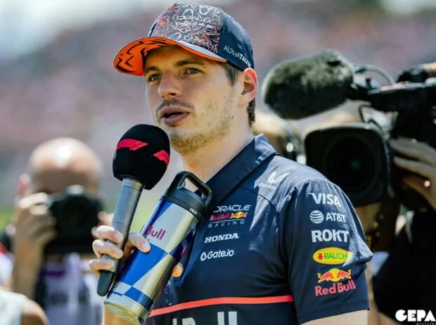 Formula 1 world champion Max Verstappen gives an interview at the Spielberg racetrack into a microphone, surrounded by cameras and TV personnel.