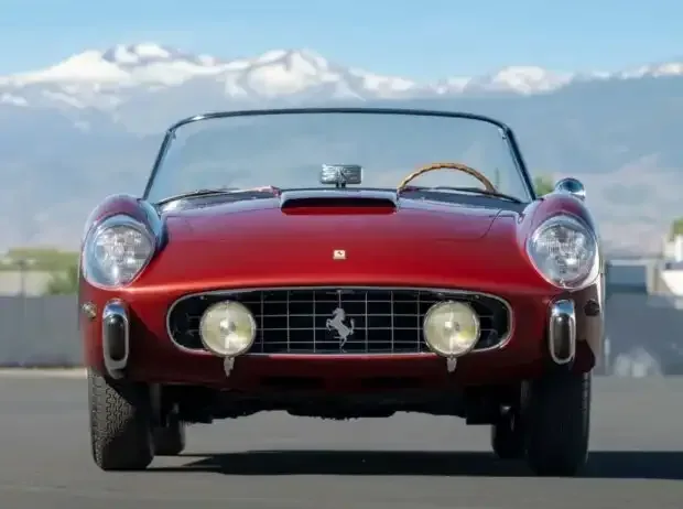 Title image for the news: Front view of a red 1958 Ferrari 250 GT Cabriolet Series I. The open vintage car stands in front of a mountain backdrop. Distinctive are the classic grille with the Cavallino Rampante, the round headlights, and the bumper guards.